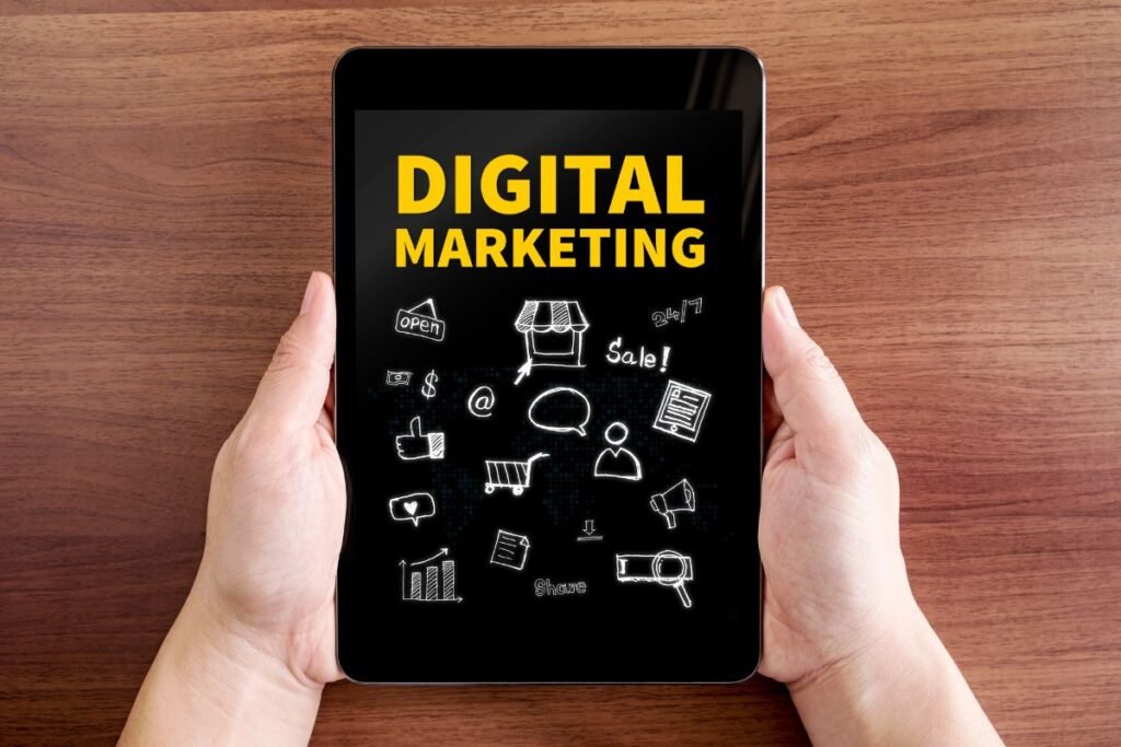 Two hands holding a tablet featuring "Digital Marketing" text and doodle icon.